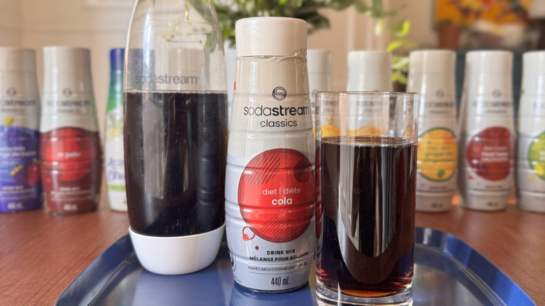 A SodaStream bottle, a syrup bottle and a Cola soda glass