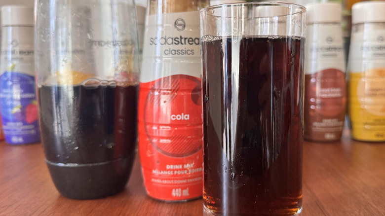 A SodaStream bottle, a syrup bottle and an orange soda glass
