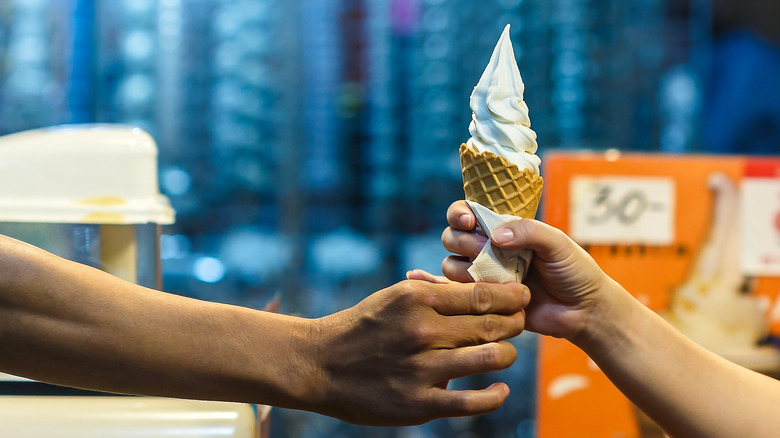 hands exchanging soft serve ice cream cone 