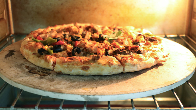 A pizza baking on a stone.