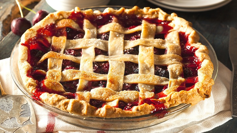 Cherry pie with lattice crust in a glass dish over a folded cloth napkin