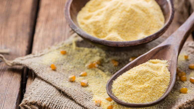 A wooden spoon and bowl filled with cornmeal