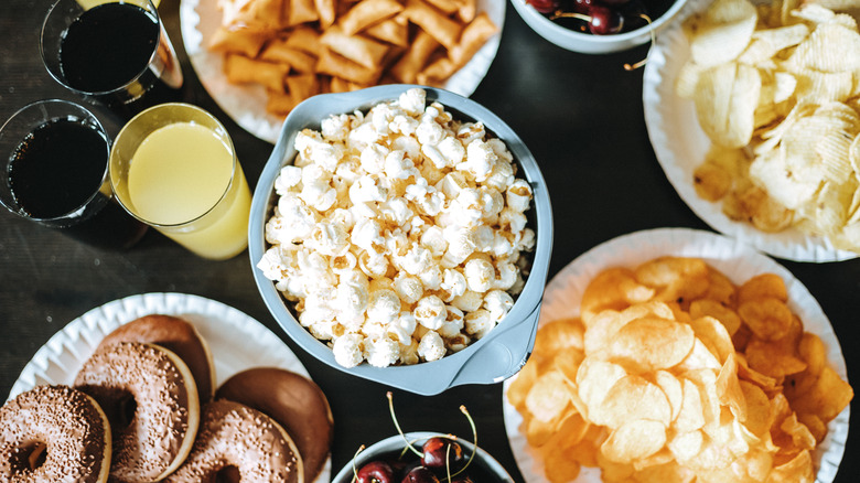 Various party snacks on a table including popcorn, chips, and donuts
