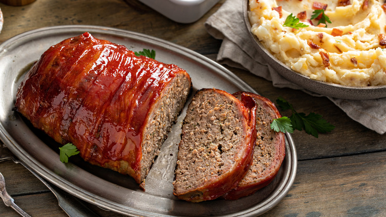 Plate of meatloaf with bowl of mashed potatoes