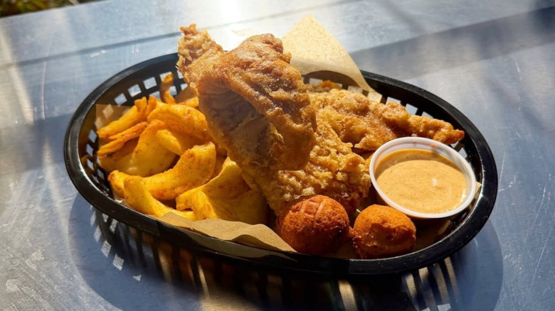 A basket platter of battered fried fish with sides and sauce.