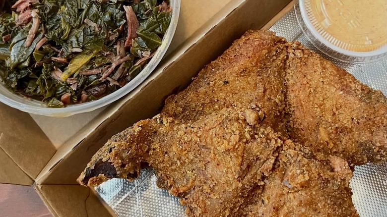 A vegetable dish and fried fish served in a takeout box.