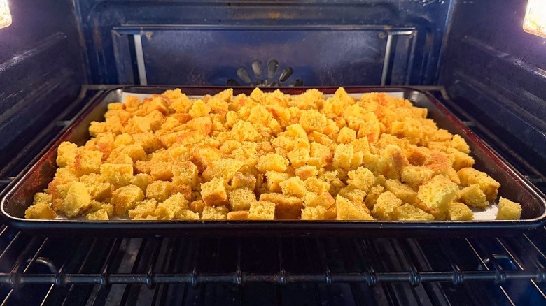 Cornbread cubes on baking sheet in oven