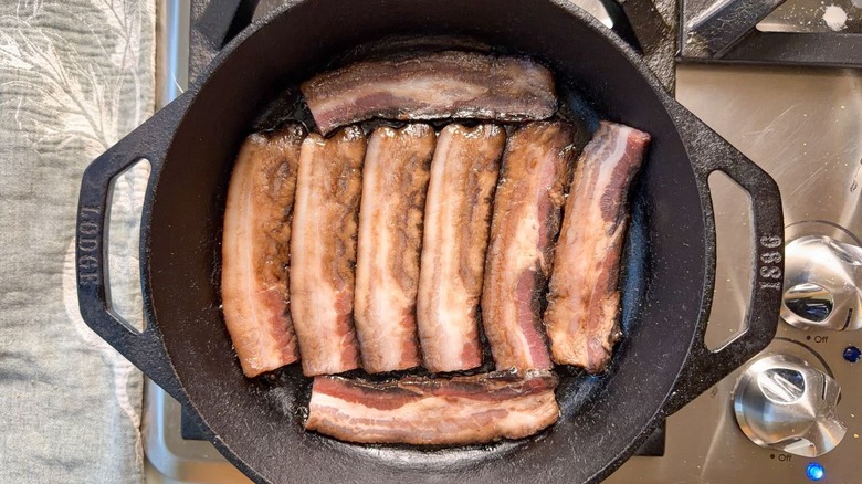 Bacon cooking in cast iron skillet on stovetop