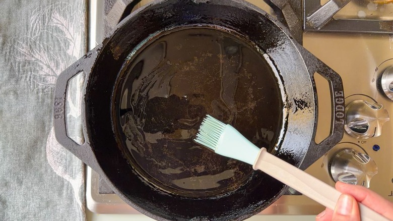 Brushing oil on a cast iron skillet on stovetop