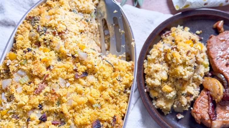 Southern-style homemade cornbread dressing in serving dish on table and on plate with pork chop