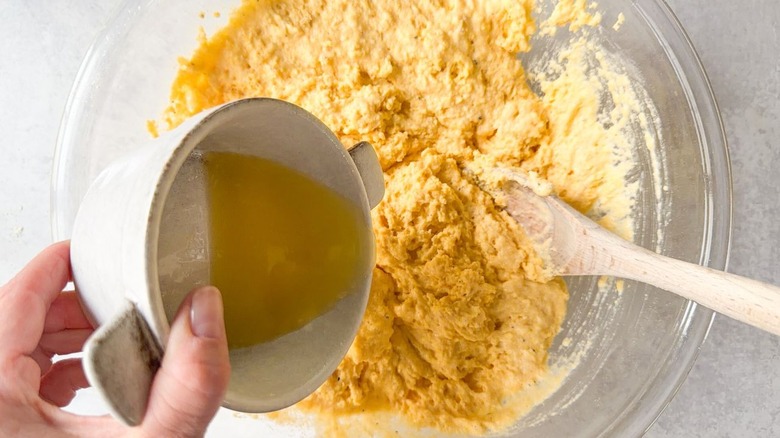 Pouring melted butter into cornbread batter