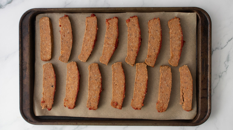 Sliced meatloaf on a parchment-lined baking sheet