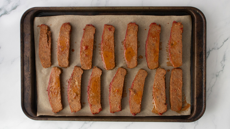 Reheated sliced meatloaf on a parchment-lined baking sheet