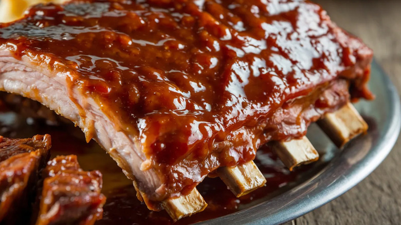 A plate of BBQ ribs is seen in close-up.