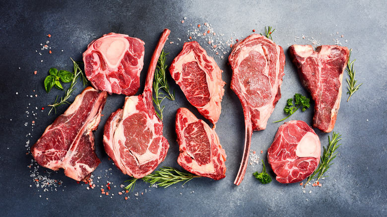 Raw steak cuts on a dark surface.
