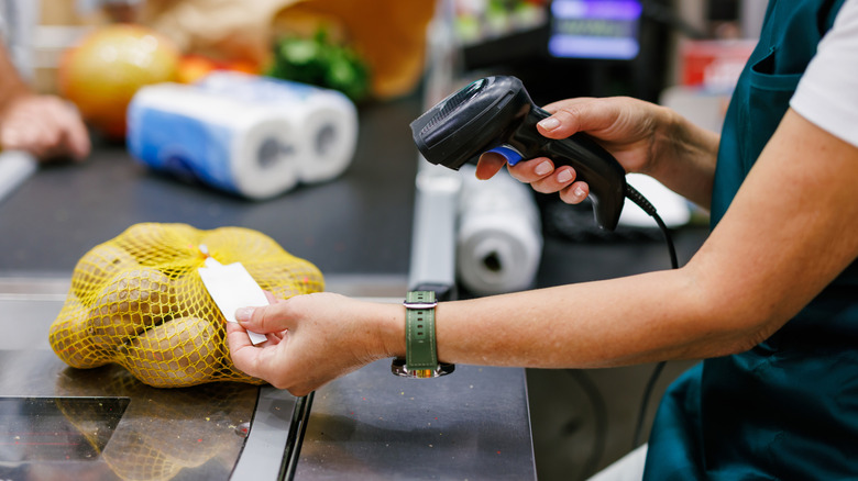 A woman scans a bag of potatoes in the checkout line