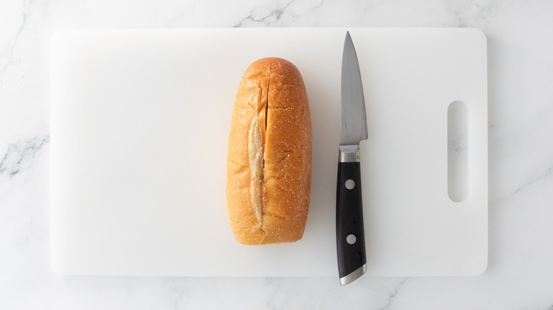 Bolillo roll and knife on cutting board