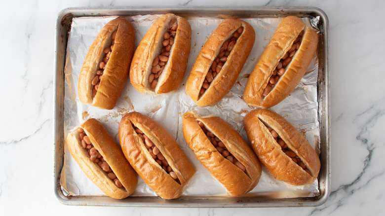 Bolillo rolls stuffed with pinto beans on baking sheet