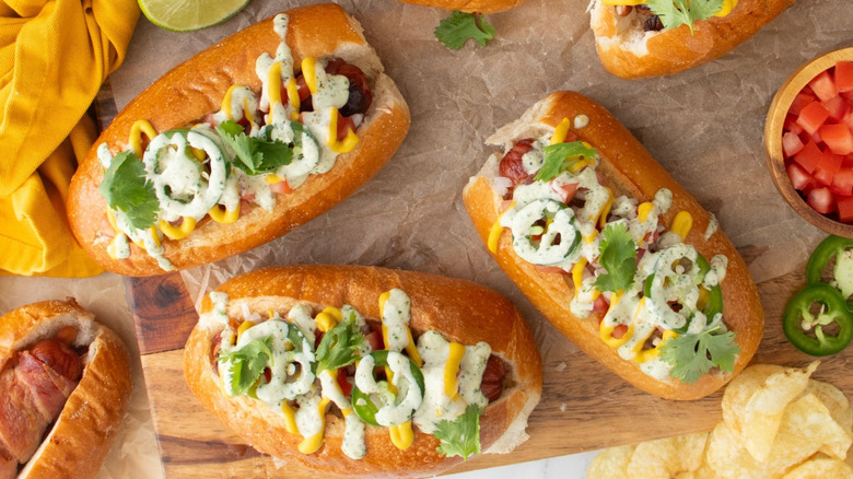 Sonoran hot dogs next to various toppings and chips