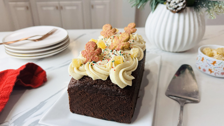 Gingerbread loaf topped with frosting, gingerbread man cookies, and candies