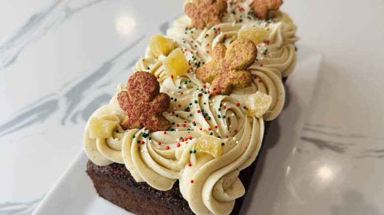 Gingerbread loaf cake decorated with frosting, gingerbread men, and candies