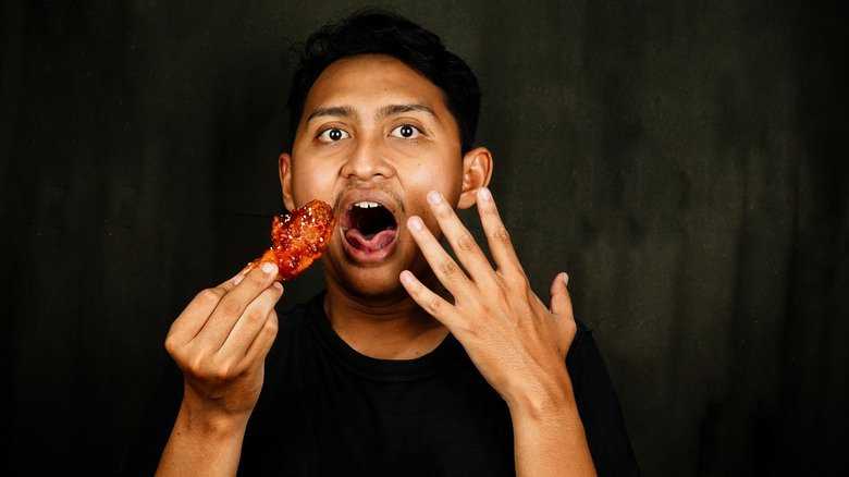 Man reacts to biting into spicy chicken wing
