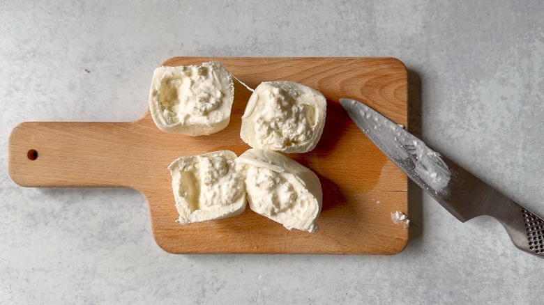 Burrata balls cut open on cutting board with knife