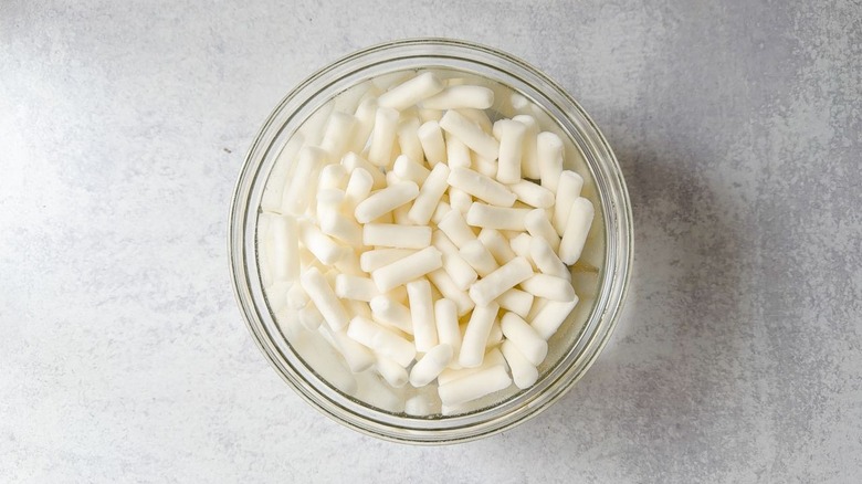 Rice cakes soaking in water in glass bowl