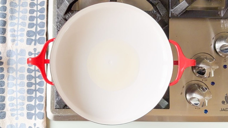 Peanut oil heating in red pan on stovetop