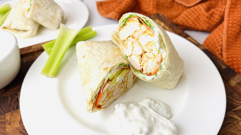 Buffalo chicken wrap on plate with celery and blue cheese dressing