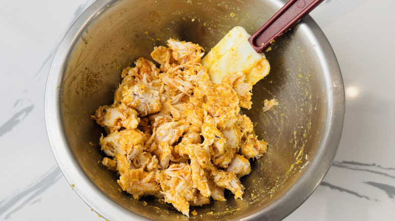 Mixing Buffalo chicken in bowl