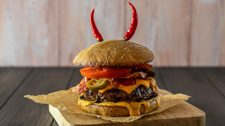 A spicy cheeseburger with chiles placed like devil horns
