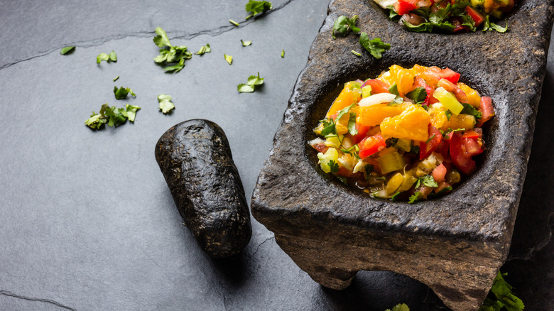 A serving of mango habanero salsa in a stone mortar and pestle with