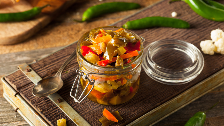 A jar of spicy giardiniera on a cutting board