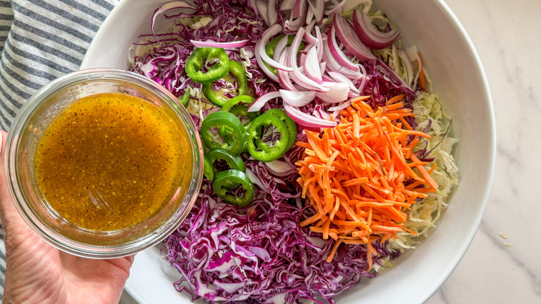 hand adding dressing to salad