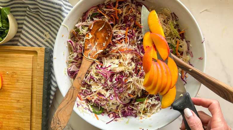 hand adding peaches to bowl