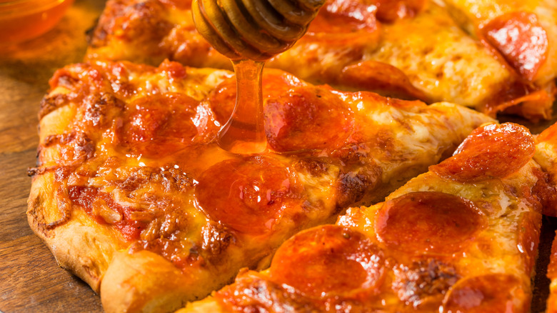 Pouring hot honey onto a pepperoni pizza