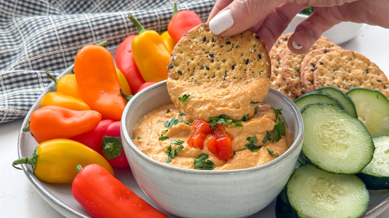 hand dipping cracker in hummus