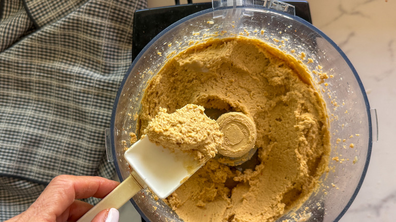 hand holding spatula with hummus