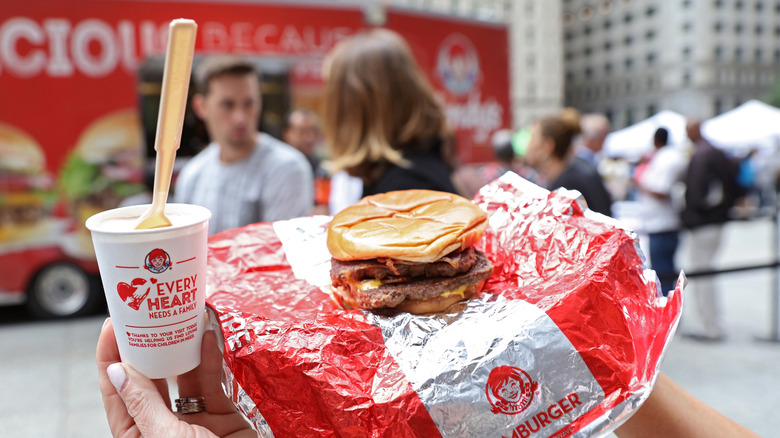 Somebody holds up a Wendy's burger