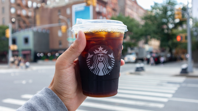 Person holding a Starbucks cold brew cup on a street