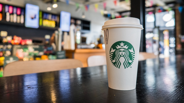 A Starbucks hot drink sitting on a table inside of a Starbucks