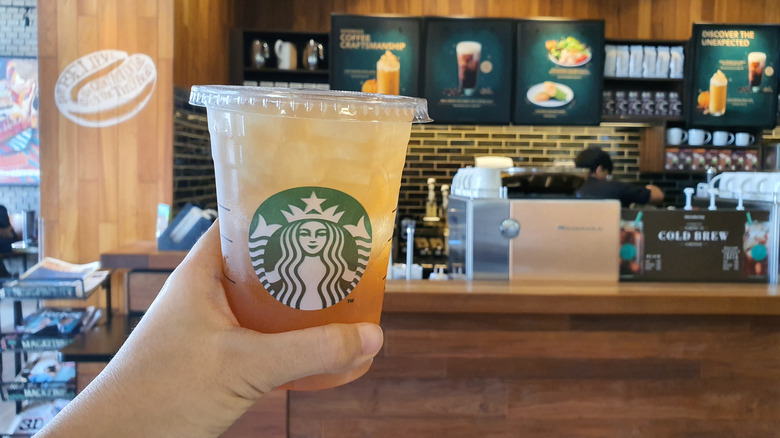 Person holding a glass of lemonade at a Starbucks store