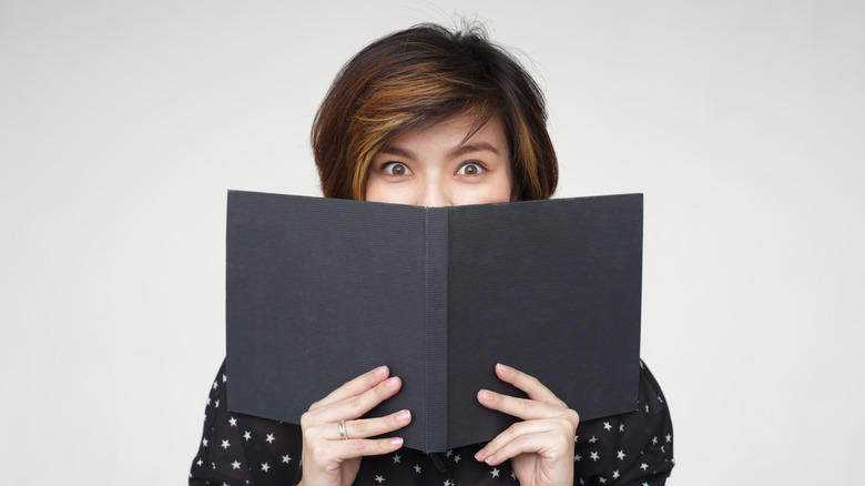 Woman hiding behind a menu
