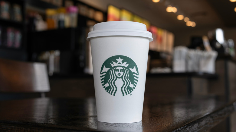 white Starbucks coffee cup on a black table inside Starbucks store