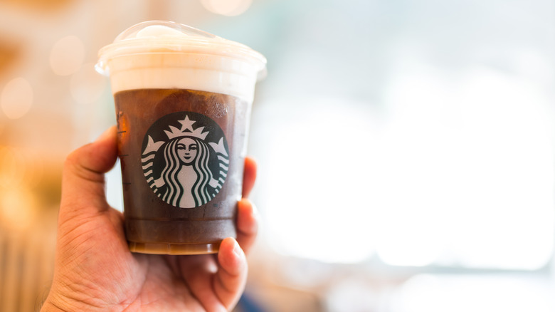 Man holding a Starbucks cold brew beverage cup in hand
