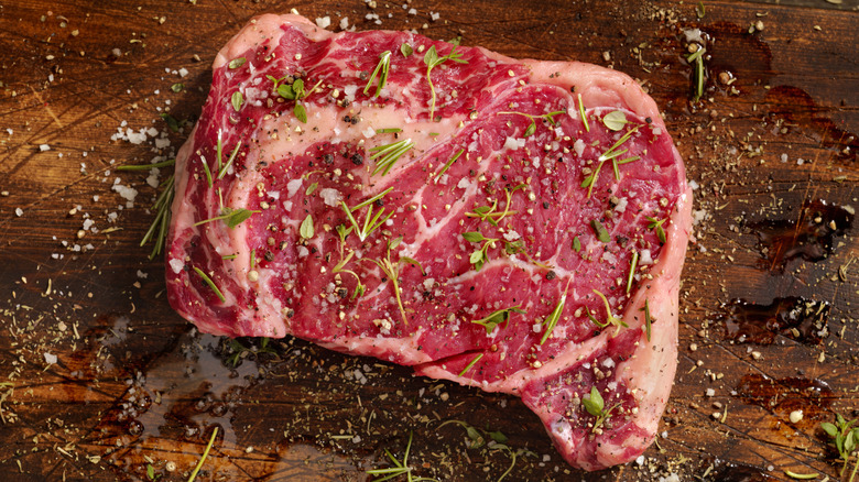 Raw ribeye steak covered in herbs and spices