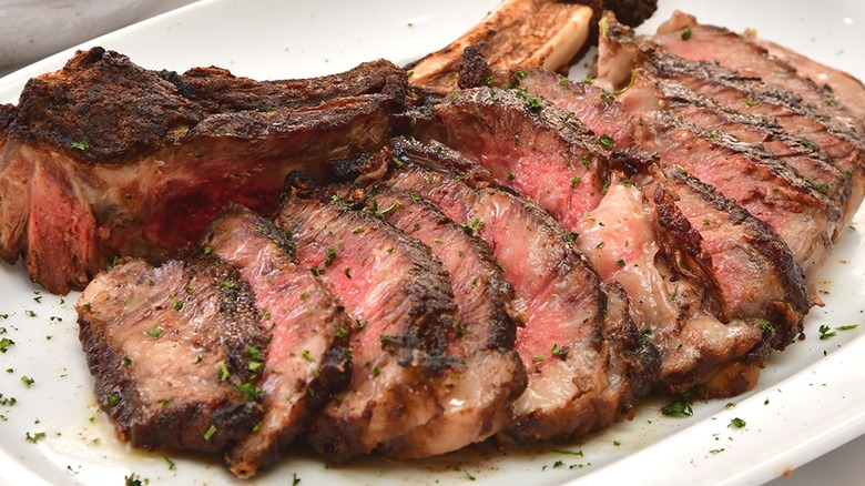Tomahawk steak sliced on white plate