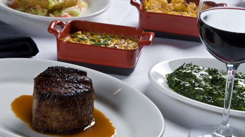 A steak, sides, and wine top a restaurant table