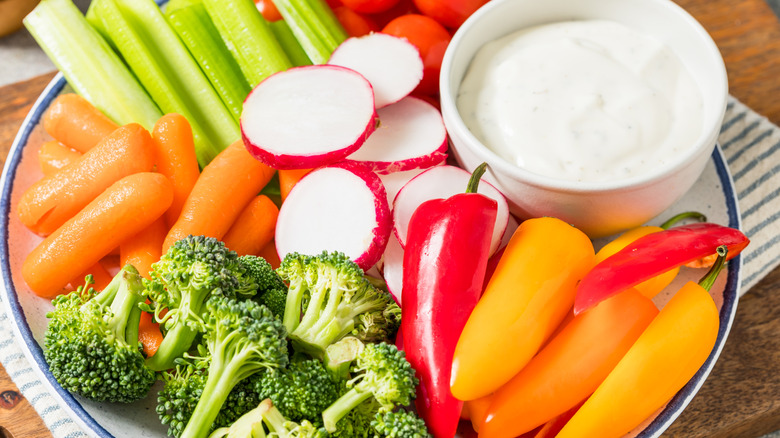 Celery, carrots, broccoli, radishes and peppers on a plate of crudités.